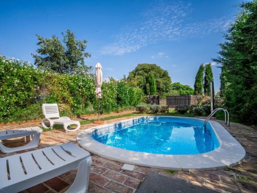 a swimming pool in a yard with two chairs and an umbrella at Holiday Home Ivanka by Interhome in Čabrunići