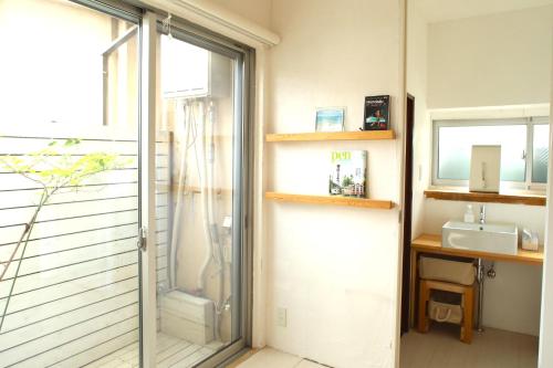 a bathroom with a glass door leading to a sink at ゲストハウスぷれぜんと in Tokyo