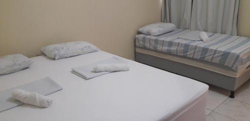 3 camas en una habitación con sábanas blancas y toallas en Casa Temporada Juazeiro Bahia, en Juazeiro