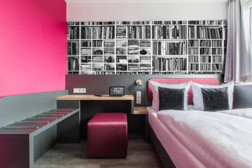 SMARTY Cologne Dom Hotel - Boardinghouse - KONTAKTLOSER SELF CHECK-IN في كولونيا: غرفة نوم بحائط وردي مع مكتب وسرير