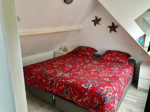 - un lit rouge avec des oreillers rouges dans une chambre dans l'établissement Sommerhaus Glücklich am Meer 2 mit Wellnesszugang, à Egmond aan Zee