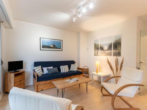 a living room with a blue couch and a tv at Apartment La Sauvagère-1 by Interhome in Carnac-Plage