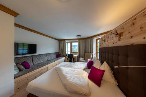 a bedroom with a large white bed with purple pillows at Hotel und Alpen Apartments mit Sauna - Bürglhöh in Bischofshofen