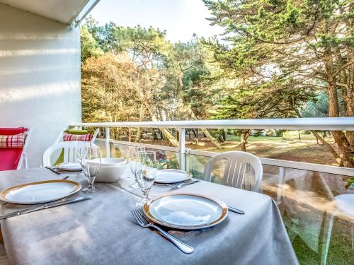 a table with plates and glasses on a balcony at Apartment Port An Dro-1 by Interhome in Carnac