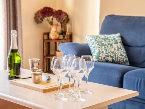 ラ・トリニテ・シュル・メールにあるHoliday Home Kerdual by Interhomeの青いソファ付きのテーブルに置かれたグラスワイン