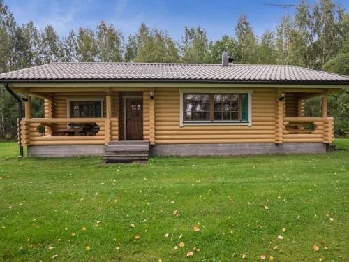 uma cabana de madeira com um jardim relvado à frente. em Holiday Home Uitonniemi- rummukkala by Interhome em Polvijärvi