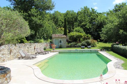une piscine avec deux chaises et un mur en pierre dans l'établissement Domaine du Roc, à Saou