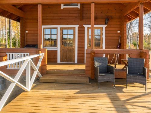 - une véranda dans une cabane en rondins avec 2 chaises dans l'établissement Holiday Home Joutsen by Interhome, à Vähäsalmi
