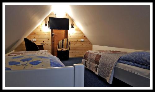 a attic bedroom with two beds and a television at Leśne Berdo 4 in Wetlina