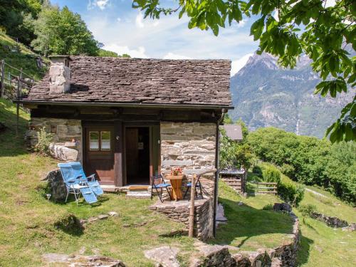 un petit cottage en pierre avec des montagnes en arrière-plan dans l'établissement Holiday Home Rustico Fey by Interhome, à Malvaglia