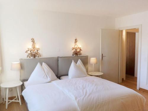 um quarto com uma grande cama branca com almofadas brancas em Apartment Chesa Cripels I by Interhome em St. Moritz
