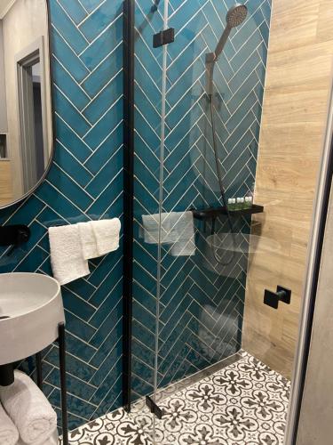 a blue tiled bathroom with a shower and a sink at Lux appartments в центре города в стиле Loft in Vinnytsya