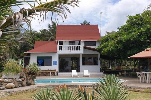 a white house with a red roof and a swimming pool at Cabaña PEDREGAL in Puerto Escondido