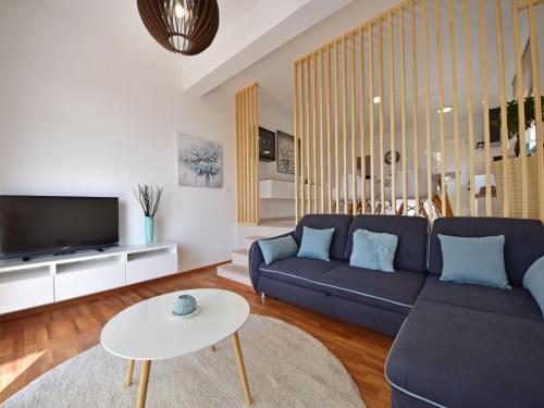 a living room with a blue couch and a tv at Apartment Cvit-2 by Interhome in Klenovica