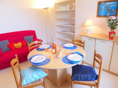 - un salon avec une table et des chaises et un canapé rouge dans l'établissement Apartment Le Petit Robinson-6 by Interhome, à La Richardais