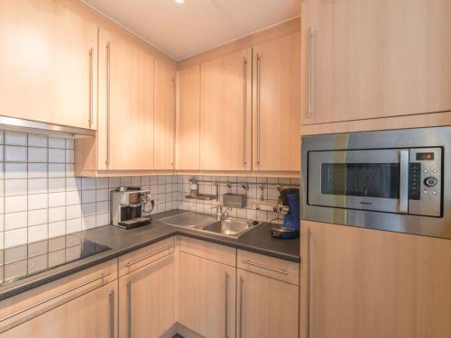 uma cozinha com armários de madeira, um micro-ondas e um lavatório em Apartment Residentie Maritiem by Interhome em Bredene