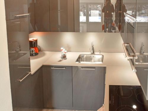uma cozinha com armários castanhos, um lavatório e um espelho em Studio Diure 0113 by Interhome em Verbier