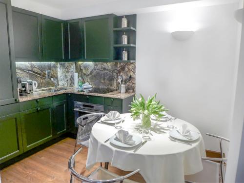 a kitchen with green cabinets and a white table with chairs at Apartment Chesa Sonnalpine B 52 by Interhome in St. Moritz