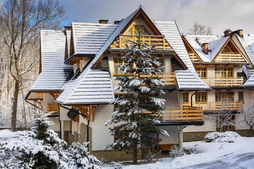 a house covered in snow with a christmas tree at Aparthotel Bellamonte in Zakopane