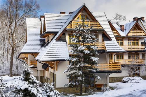a house covered in snow in the winter at Aparthotel Bellamonte in Zakopane