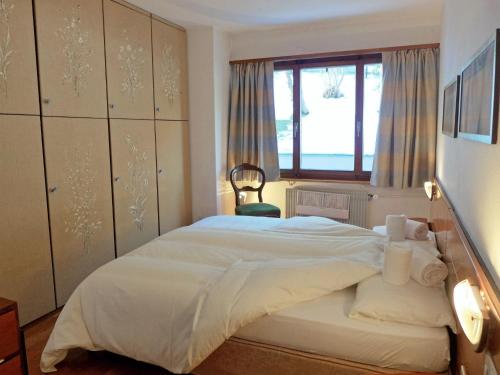 1 dormitorio con 1 cama blanca grande y ventana en Apartment Chesa Arlas A1 by Interhome, en St. Moritz