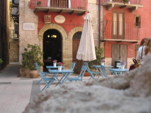 an umbrella and tables and chairs in front of a building at Antica Dimora San Girolamo in Licata