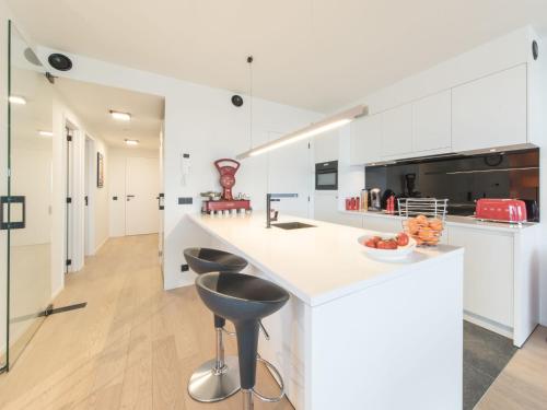 una cocina con armarios blancos y una barra con taburetes en Apartment Victoria by Interhome, en Ostende