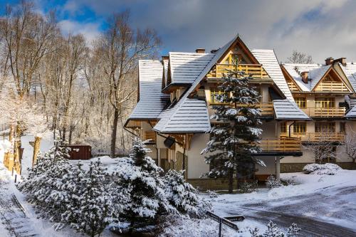 a wooden house with snow on the roof at Aparthotel Bellamonte in Zakopane