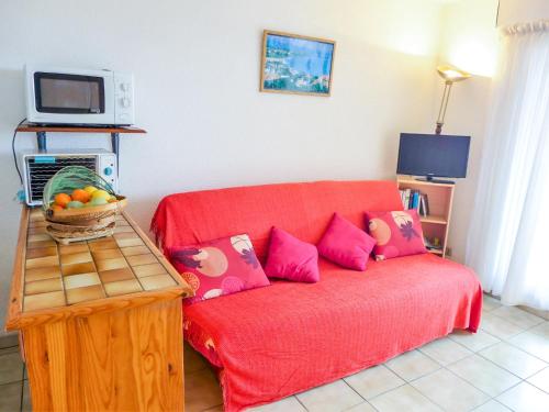 un sofá rojo con almohadas rosas en la sala de estar. en Apartment Zirlinga-7 by Interhome, en Bidart