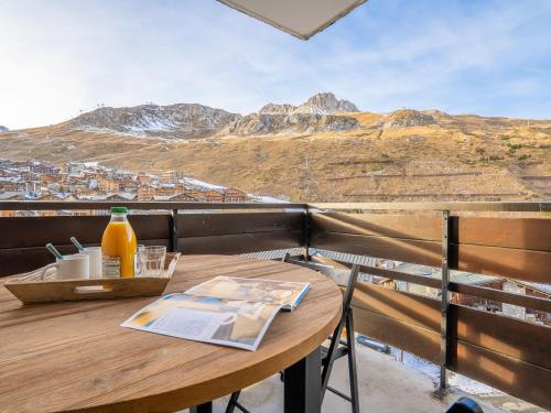a wooden table with a drink on a balcony with mountains at Studio Le Grand Pré-5 by Interhome in Tignes