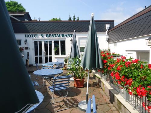 a patio with tables and umbrellas in front of a hotel and restaurant at Das FRITZ Hotel Schwerin schöne Lage im Grünen mit regionaler Küche kostenfreien Parkplätzen und E Ladestation in Schwerin