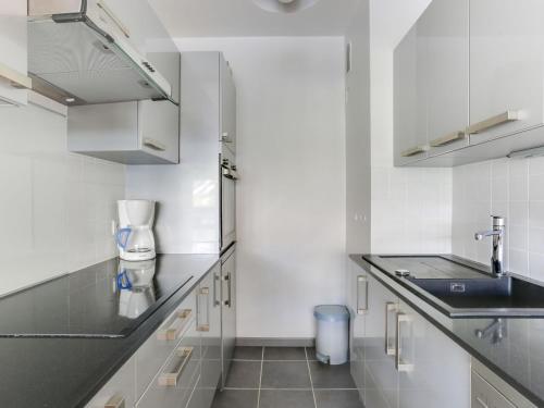 eine Küche mit weißen Schränken und einem Waschbecken in der Unterkunft Apartment Le Bec Rouge - Le Lac-5 by Interhome in Tignes