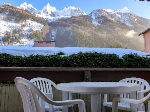 une table et des chaises sur un balcon avec des montagnes enneigées dans l'établissement Apartment Ginabelle 1-1 by Interhome, à Chamonix-Mont-Blanc