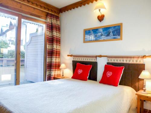 een slaapkamer met een bed met rode kussens en een raam bij Apartment Ginabelle 1-1 by Interhome in Chamonix-Mont-Blanc