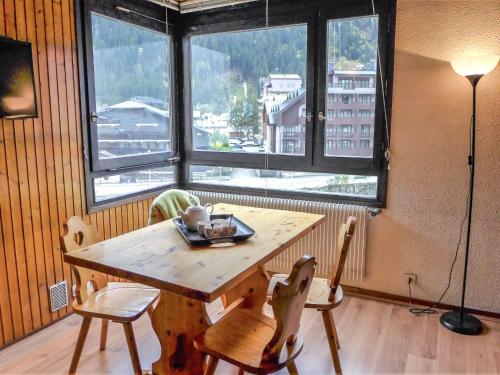 une table et des chaises dans une pièce avec une grande fenêtre dans l'établissement Studio L'Aiguille du Midi-7 by Interhome, à Chamonix-Mont-Blanc