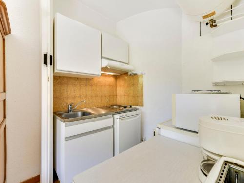 une petite cuisine avec des armoires blanches et un évier dans l'établissement Studio Antares-2 by Interhome, à Cavalaire-sur-Mer