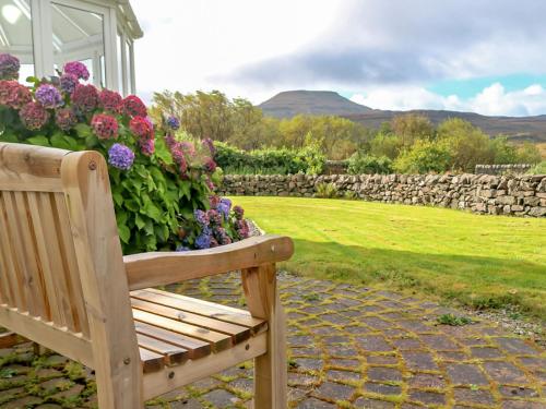 a wooden bench sitting next to a bunch of flowers at Holiday Home Dunvegan House by Interhome in Dunvegan