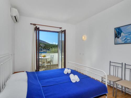 Schlafzimmer mit einem Bett mit blauer Bettwäsche und einem Balkon in der Unterkunft Apartment Cico-1 by Interhome in Selca kod Bogomolja