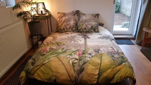 a bedroom with a bed with a tropical bedspread at Gite See You Soon - Maisonnette Green Lodge in Ribeauvillé