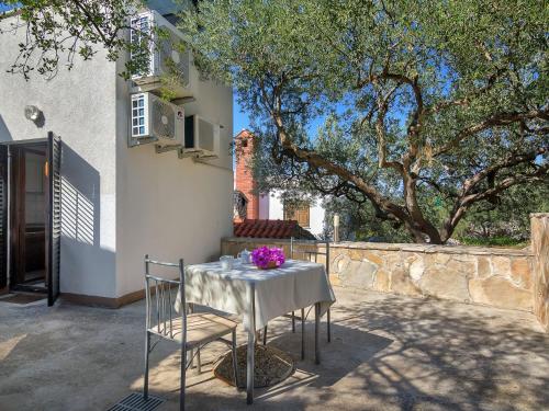 een tafel met een wit tafelkleed en paarse bloemen erop bij Apartment Cico-8 by Interhome in Selca kod Bogomolja