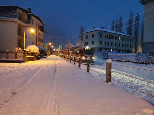 a train traveling down a snow covered street at night at Residenza Le Torri in Tirano