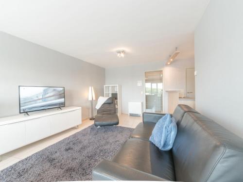 a living room with a leather couch and a flat screen tv at Apartment Queen Mary 302 with balcony by Interhome in Bredene