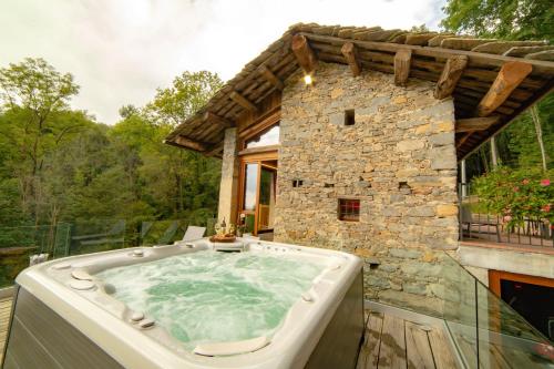 a hot tub on a patio with a stone building at Baita Relais La Cesarina in Vico Canavese