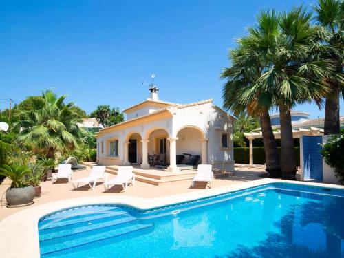 a villa with a swimming pool and palm trees at Holiday Home Casa Kate by Interhome in Calpe