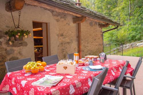 a table with a red table cloth with fruit on it at Baita Relais La Cesarina in Vico Canavese