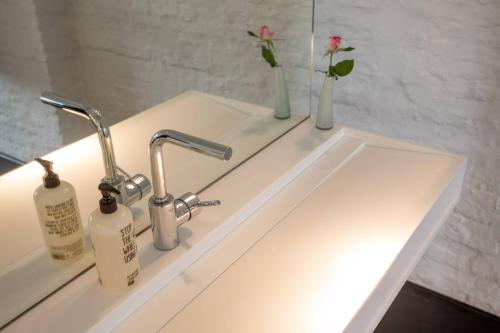 a bathroom sink with two faucets and a mirror at B&B Suites FEEK in Antwerp
