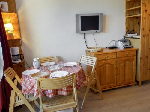 a dining room table with chairs and a tv on top at Studio Soyouz Vanguard-81 by Interhome in Le Corbier