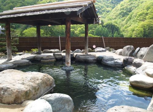a pond with rocks and a gazebo at Okada Ryokan Warakutei in Takayama