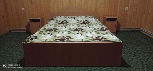a bed in a room with a bedvisor with a bedspread with flowers at Садиба Лісовичок in Yaremche