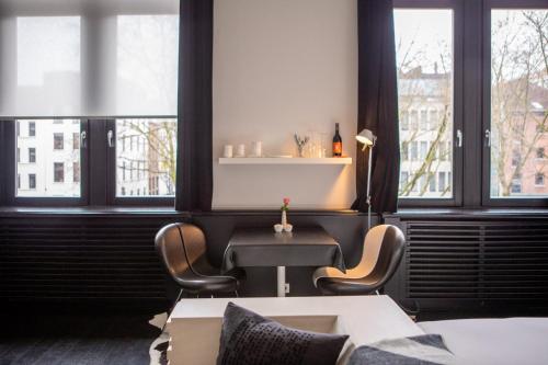a room with a table and chairs and windows at B&B Suites FEEK in Antwerp